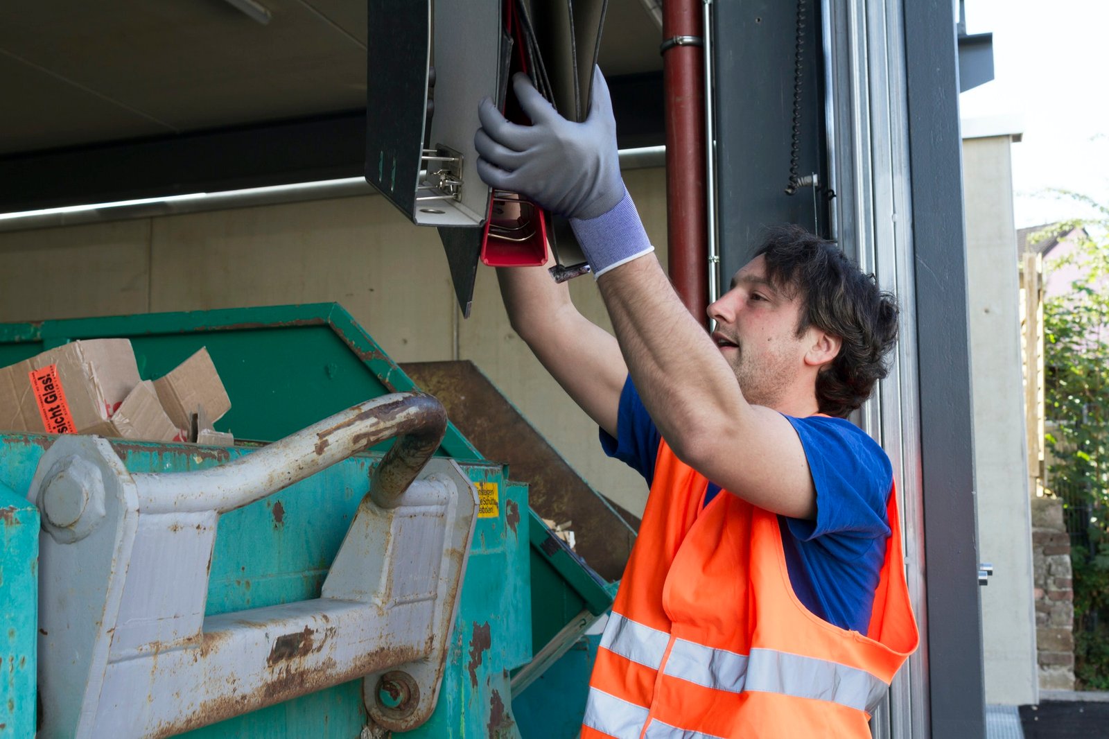 worker-at-a-waste-container-throwing-away-folders.jpg